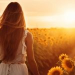 A woman walking through a field of sunflowers.