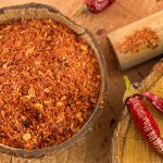 Both ground and whole cayenne peppers on a counter.