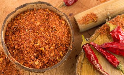 Both ground and whole cayenne peppers on a counter.