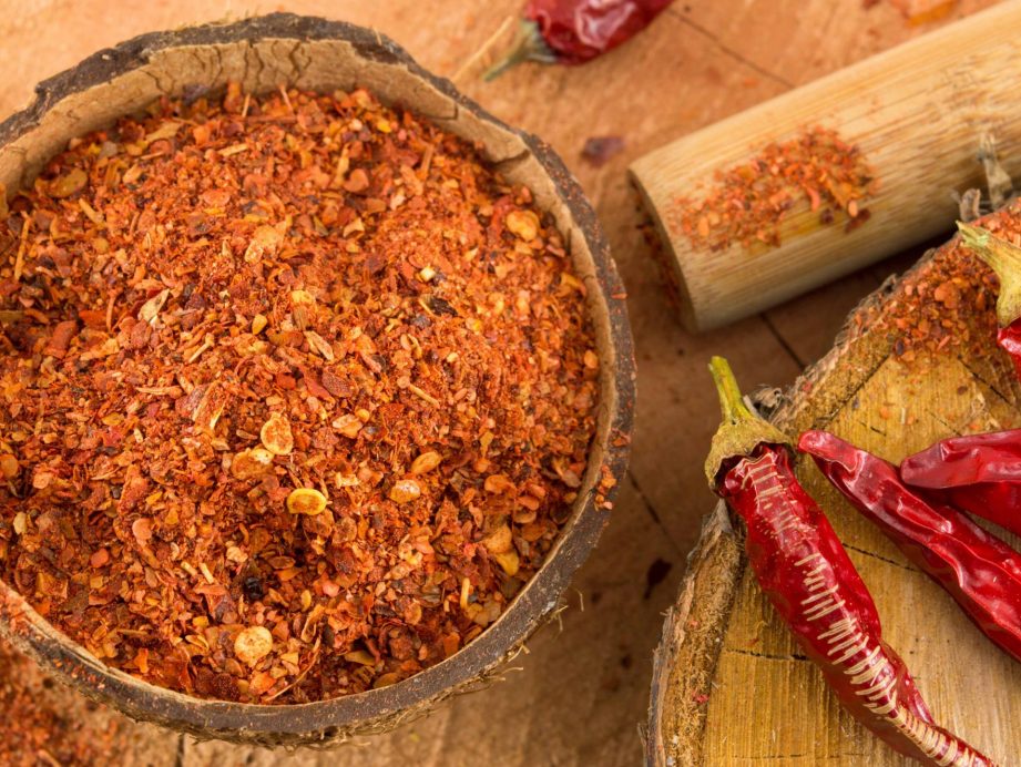 Both ground and whole cayenne peppers on a counter.