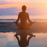 a silouette of a woman doing yoga on the beach