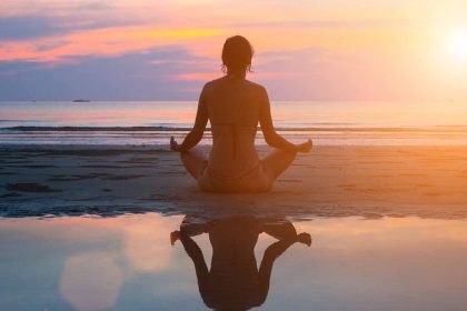 a silouette of a woman doing yoga on the beach