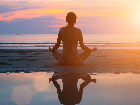 a silouette of a woman doing yoga on the beach