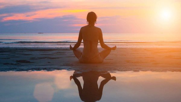 a silouette of a woman doing yoga on the beach