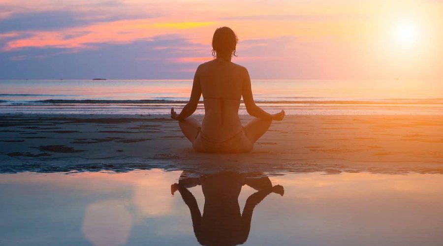 a silouette of a woman doing yoga on the beach