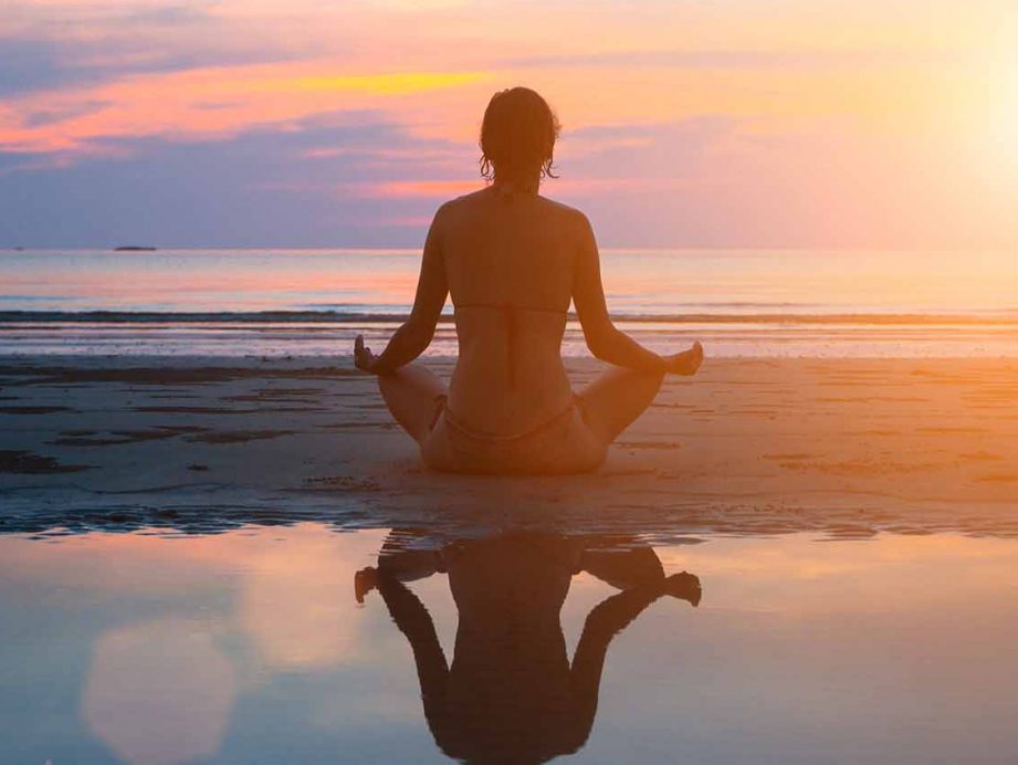 a silouette of a woman doing yoga on the beach