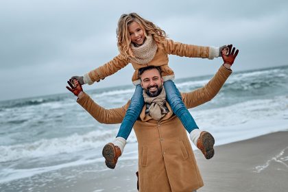 A dad carrying his daugher on his shoulders