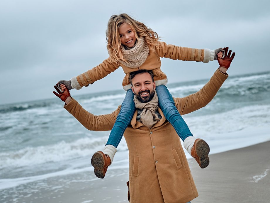 A dad carrying his daugher on his shoulders