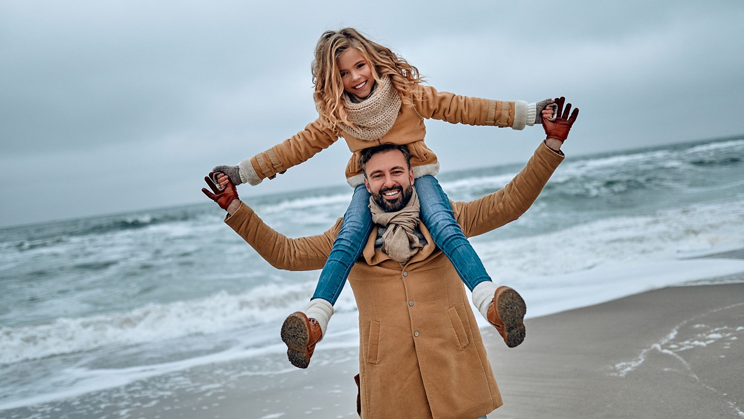 A dad carrying his daugher on his shoulders